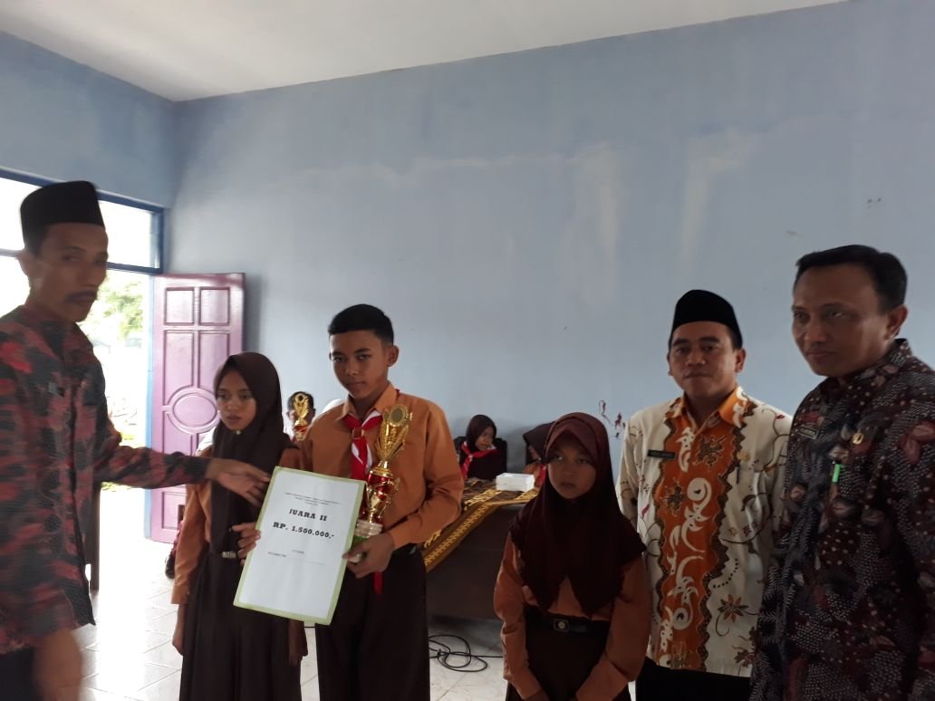 Foto:Drs. Fajarisman, MH selaku Kepala Bidang Pembinaan SD, saat menyerahkan tropi