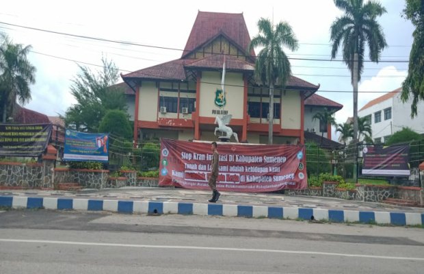 Foto: Suram, seorang petugas Satpol PP lewat di depan gedung DPRD Sumenep yang ditempeli Banner kritikan mahasiswa