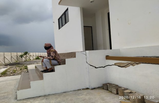 Foto : Seorang warga duduk diatas tangga di gedung DPRD yang retak