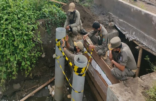 Foto: Petugas saat memasang tanda ditutup di saluran pembuangan limbah tambak udang PT Bumi Subur 