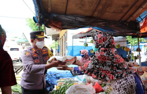  Foto: Kapolres Batu AKBP Catur Cahyono Wibowo, SIK, MH, saat tengah membagikan bantuan paket sembako berupa beras kepada salah seorang pedagang.