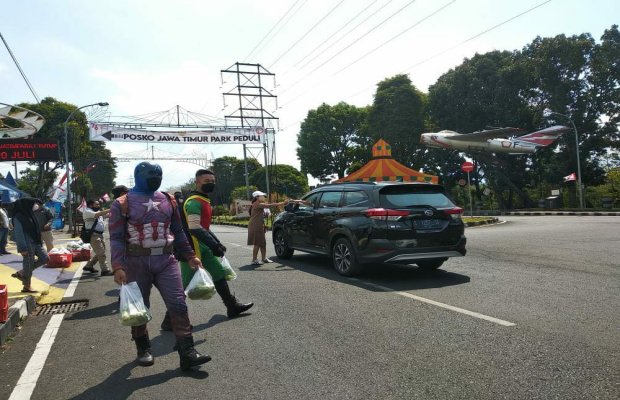 Foto: Humas Laskar Foundation Jatim Park Group, Nhia Hapsari saat tengah membagikan sayuran kepada pengendara yang melintas.