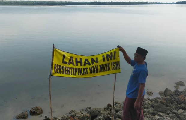 Foto: Salah satu warga menunjuk benner di area pantai Gersik Putih