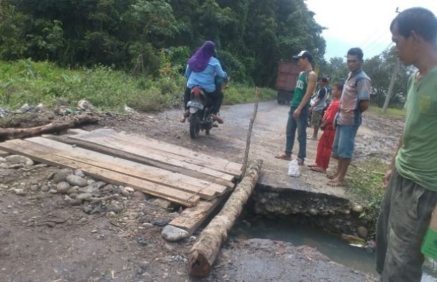 Foto: warga sedang memperbaiki jembatan rusak
