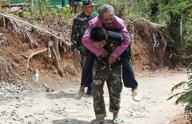 Foto: Satgas TMMD Trenggalek saat menggendong warga sedang sakit ke posko kesehatan