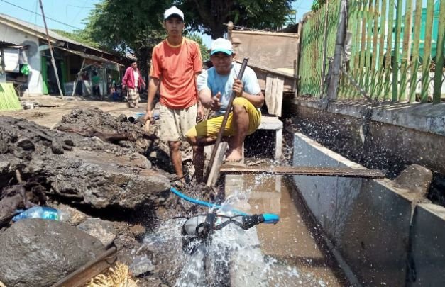 Foto: salah seorang warga sedang memperbaiki pipa PDAM yang bocor