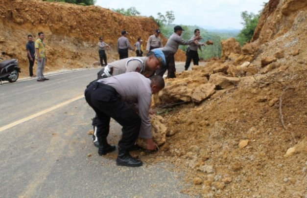Foto: Polisi sedang bergotong royong membersihkan material longsor di Jl Lingkar Utara, Desa Kebunan, Sumenep