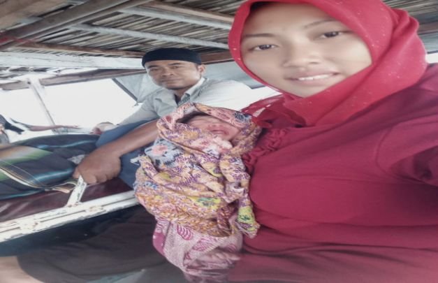 Foto: Bidan Gesi Variana Sari, menggendong bayi padiennya diatas perahu