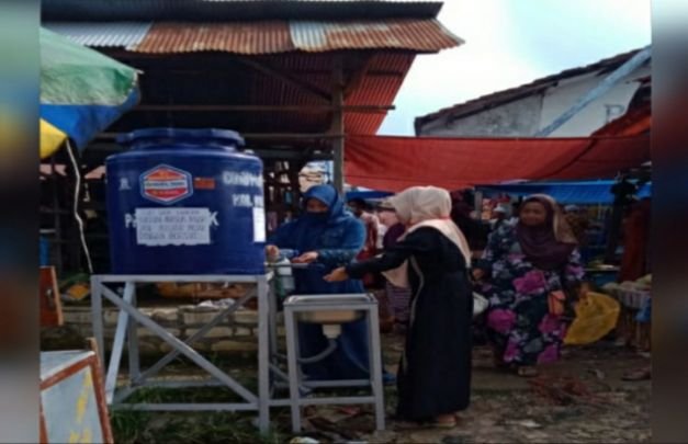 Foto : seorang pengunjung pasar membasuh tangan setelah berbelanja. 