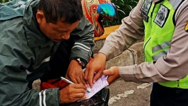 Polisi sedang menilang seorang pengendara motor yang terjaring Operasi Patuh Jaya di Jalan R.E. Martadinata, Cikarang Utara, Kamis (26/4/2018).