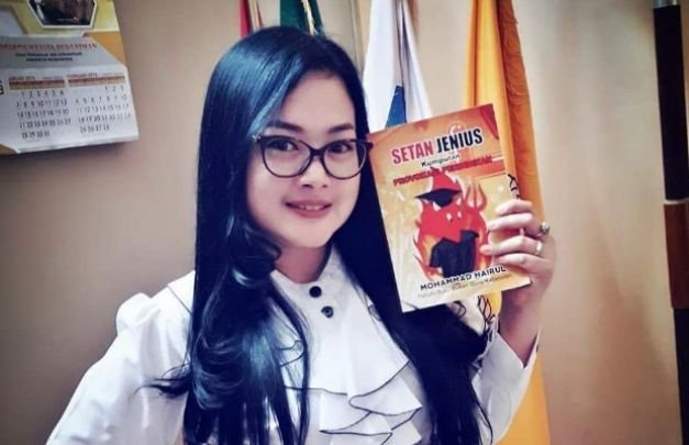 Foto: Seorang Gadis sedang memperlihatkan buku setan jenius karya Hairul