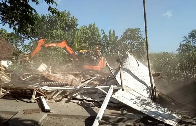 Foto: tampak sebuah alat berat sedang merobohkan bangunan semi permanes di Lokalisasi 'Bebe'an' di lumajang 