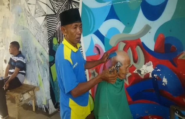 Foto: Sabrawi Saat Mencukur Rambut Pelanggan Tetapnya