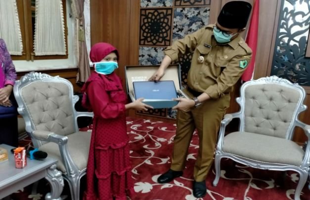 Foto: Bupati Pamekasan, Baddrut Tamam (kanan) saat memberikan hadiah laptop kepada Alfiatus Sholehah, peraih juara III lomba menulis surat untuk Mendikbud, Nadiem Makarim
