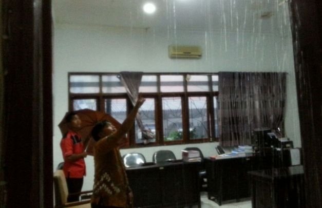 Foto: Dua staf fraksi Gerindra Sejahtera  sedang mengawasi air hujan yang masuk