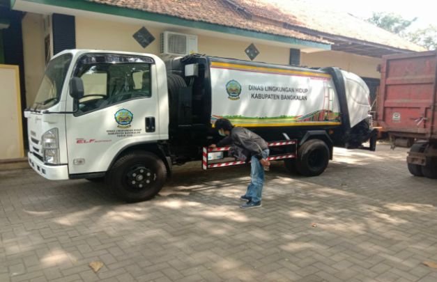 Foto : Salah seorang warga melintas didepan mobil compactor. 