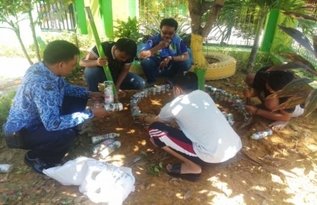 Foto: Lurah Patemon Bersama Stafnya Saat Memasang Sampah Plastik Yang Dimasukkan Dalam Botol Air Meneral di Lingkungan Kantornya