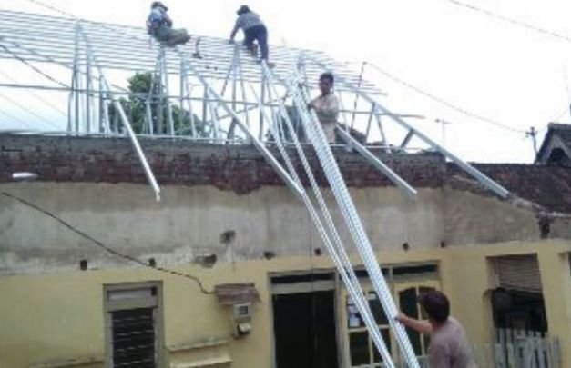 Foto: Aiptu Lasmito saat bantu pasang atap rumah warga