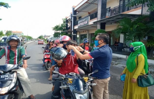 Foto: Hairul Anwar saat memasangkan masker kepada pengendara
