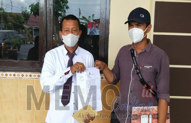  Foto : pelapor didampingi Kabiro Lacakpos menunjukkan laporan polisi di depan Mapolres Sampang