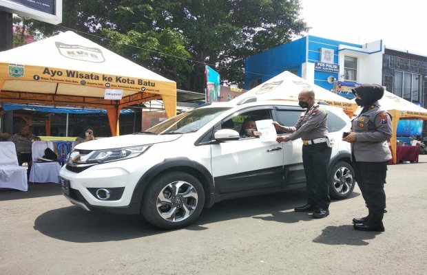 Foto: Kanit Regident Satlantas Polres Batu saat memberikan sertifikat vaksinasi kepada lansia 