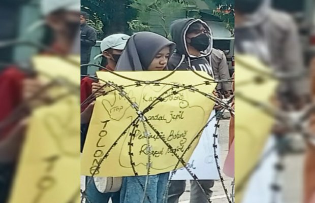 Foto: Salah seorang pendemo perempuan sedang memegang poster penolakan HCML