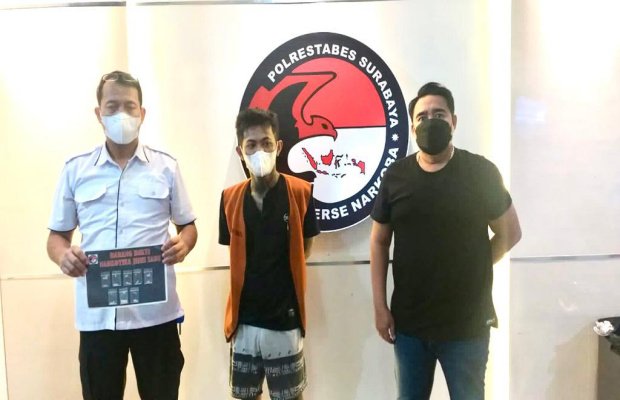 Foto: tersangka ditengah diapit dua petugas dengan menunjukan barang buktinya.
