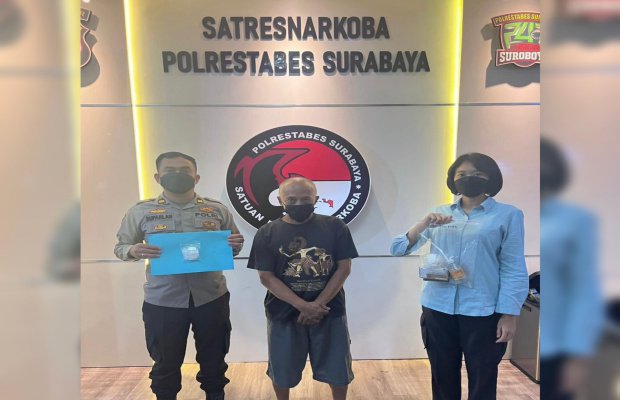 Foto: tersangka ditengah diapit dua petugas dari Polrestabes Surabaya