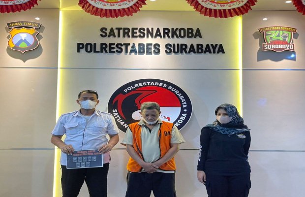 Foto: tersangka ditengah dengan diapit dua petugas kepolisian menunjukan barang buktinya.