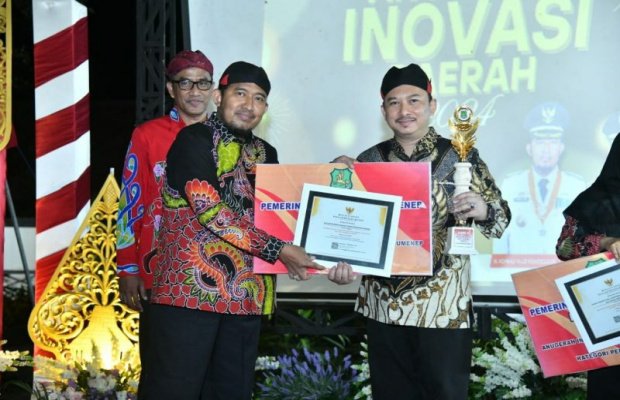 Foto: Bupati Sumenep, Achmad Fauzi Wongsojudo, didampingi Kepala Badan Riset dan Inovasi Daerah (Brida), Benny Irawan, saat menyerahkan piagam penghargaan kepada Kepala Bappeda, Arif Firmanto