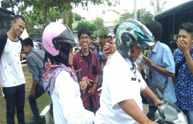 Foto : laili Akmaliyah, Kabid Penganggaran BP2KD Sampang, dibonceng rekannya terburu buru meninggalkan awak media di halaman Polres Sampang