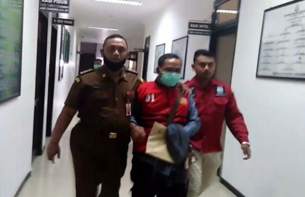 Foto: Mantan Kades Purorejo (tengah) diapit petugas saat hendal diberangkatkan ke rutan kelas 1 Medaeng Surabaya