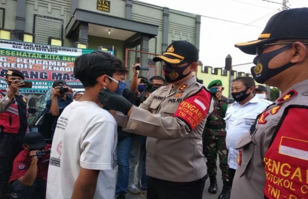 Foto:Kapolres Batu AKBP Harviadhi Agung Prathama, SIK, MIK saat memakaikan masker kepada warga 