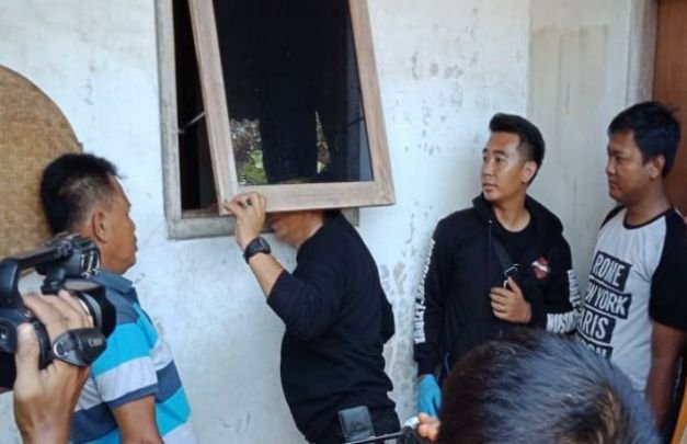 Foto:  AKP. Hasran Cobra, Ka. Tim Cobra Polres Lumajang melakukan olah TKP. Mengecek jendela tempat pelaku masuk rumah korban
